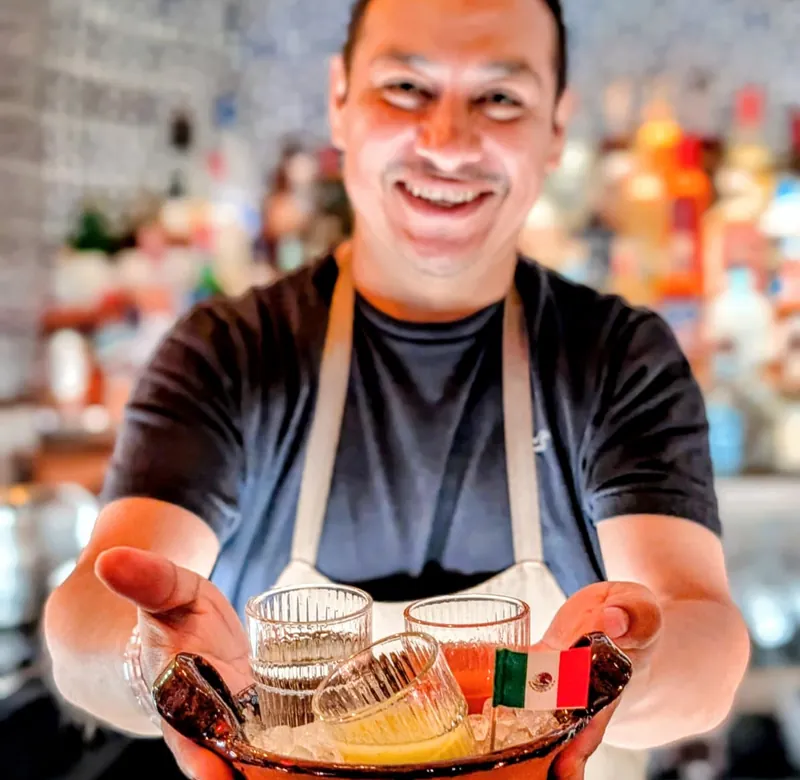 Bartender presenting drinks during a Green House on-premise bar activation.